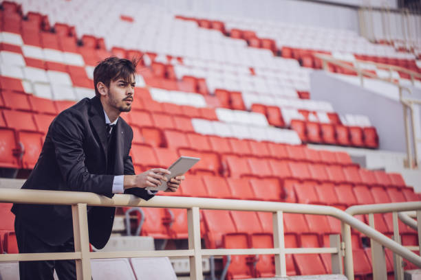 Manager man standing on stadium and holding digital tablet